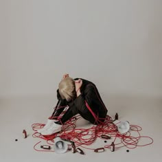 a person sitting on the ground surrounded by wires and headphones, with their eyes closed