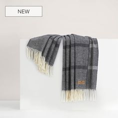 a gray and white plaid scarf hanging on a wall next to a sign that says new