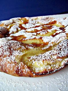 a pastry with powdered sugar on it sitting on a white plate next to a blue wall