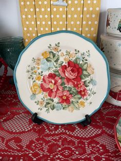 a plate with flowers painted on it sitting on a red tablecloth next to other plates