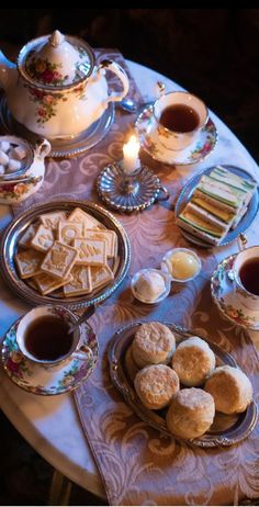 a table topped with plates and cups filled with food next to a tea pot on top of a table