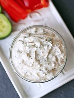 a small glass bowl filled with dip next to sliced cucumbers