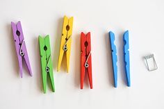 four pairs of scissors are lined up next to each other on a white surface with a metal clip in front of them