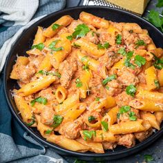 a skillet filled with pasta and meat sauce on top of a blue table cloth