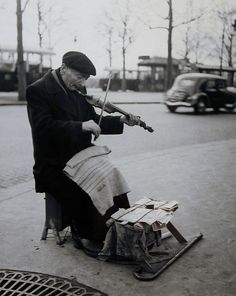 an old man is playing the violin on the street