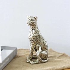 a statue of a leopard sitting on top of a table next to a laptop computer