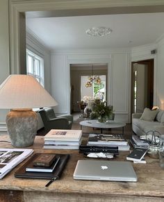 a living room filled with furniture and a table topped with laptops next to a lamp