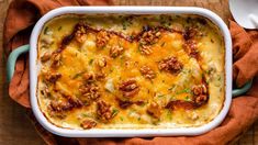 a casserole dish with meat, cheese and nuts in it on a wooden table