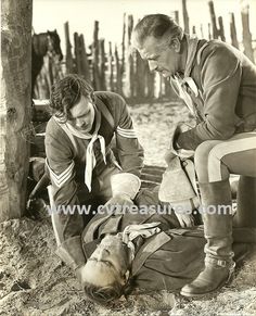 an old black and white photo of two men tending to a dog on the ground