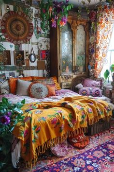 a bed with colorful blankets and pillows in a room filled with flowers on the wall