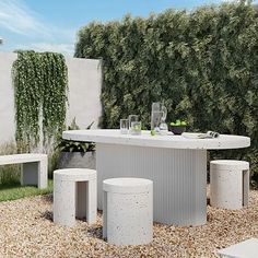 an outdoor dining table with four stools in the middle of graveled area next to shrubbery