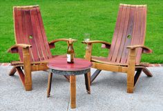 two wooden chairs sitting next to each other near a table with a bottle on it