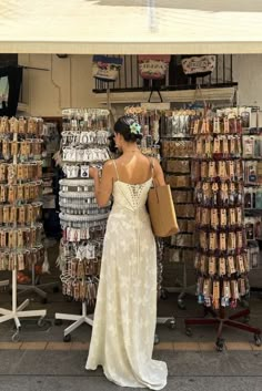 a woman standing in front of a store looking at items on the shelves and wearing a dress