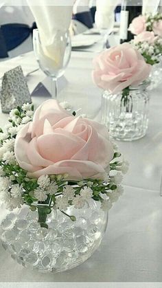 several vases filled with pink roses and white flowers on a long table set for an event