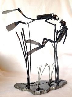 a sculpture made out of metal sticks and other items on a white surface with a white background