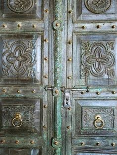 an ornate wooden door with metal handles and knobs