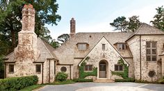 a large brick house surrounded by greenery and stone driveway with an arched doorway leading to the front door