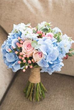 a bouquet of blue and pink flowers sitting on top of a couch