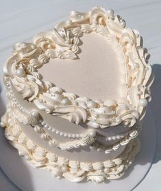 a heart shaped cake with pearls on the top is sitting on a white tablecloth