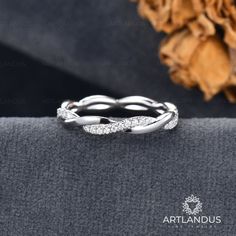 a white gold wedding band with diamonds on the top and bottom, sitting on a piece of cloth