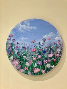 a painting of flowers on the side of a wall with blue sky in the background