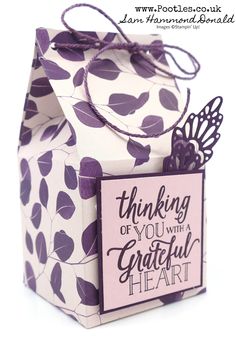 a small gift bag with purple leaves on it and a tag that says thinking of you with a grateful heart