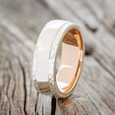 a white and gold wedding ring on top of a wooden table