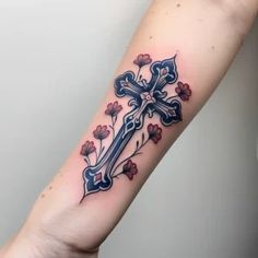 a cross tattoo on the arm with flowers