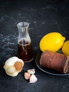 garlic, lemons and oil on a plate next to an onion peel with some other ingredients