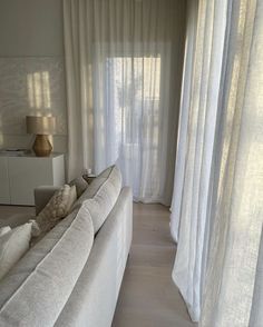 a living room filled with furniture and white curtains