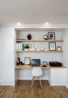 a desk with two computers on top of it and some pictures above the desk in front of it