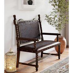 a wooden chair sitting on top of a rug next to a potted plant and vase