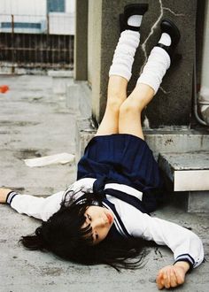 a woman laying on the ground with her feet up in the air next to a building