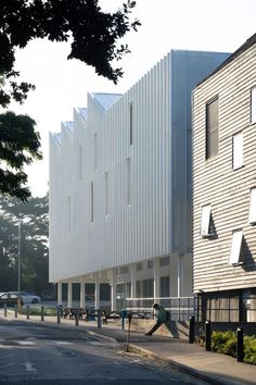 the building has many windows on it and people are walking down the street in front