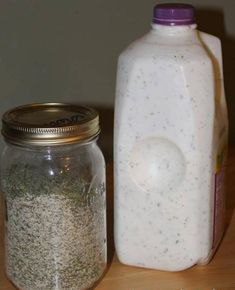 there is a glass bottle next to a jar with some sand in it on the table