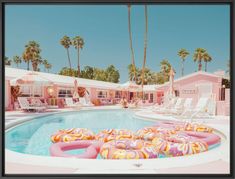 a pool with inflatable floats and palm trees around it, near pink motels