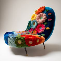 a brightly colored chair with flowers on the back and legs, sitting in front of a white background