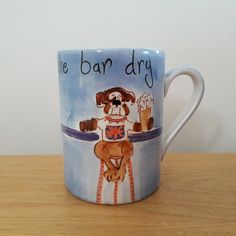 a coffee mug with a dog on it sitting on a table next to a wall