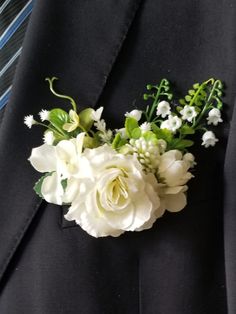 a man wearing a suit and tie with white flowers on it's lapel