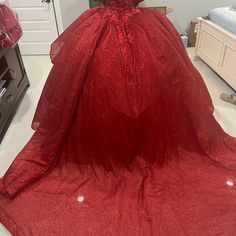 a red ball gown is on display in a room with white walls and flooring