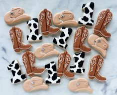 decorated cookies in the shape of cowboy boots on a marble countertop with white and brown icing