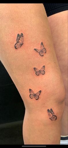 a woman's thigh with three butterflies on the back of her leg, and one is