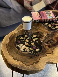 a wooden table with a candle on top of it next to a book and a cup