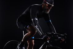 a bearded man riding a bike on a black background in the dark with no helmet