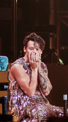 a man sitting on top of a stage holding his hands to his face