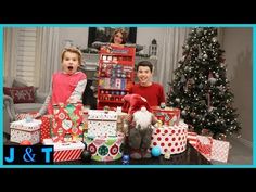 two children are posing with presents in front of a christmas tree and other holiday decorations