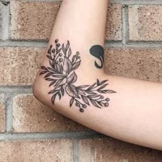 a black and white photo of a woman's arm with flowers on it, next to a brick wall