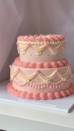 a three tiered cake with pink icing and ruffles on the sides