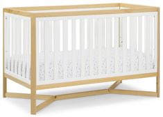 a wooden crib with white sheets on the bottom, and no mattress in it