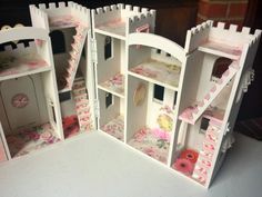 the doll house is made out of cardboard and has pink flowers on it's walls